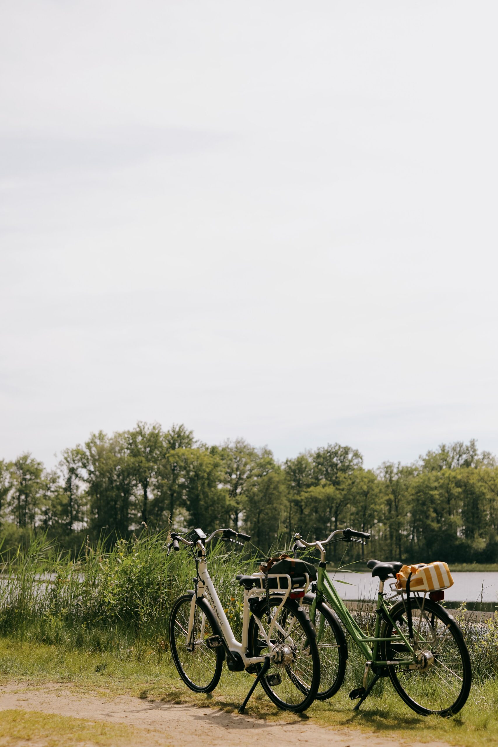 Two bicycles parked by a serene riverside under clear skies, inviting adventure.
